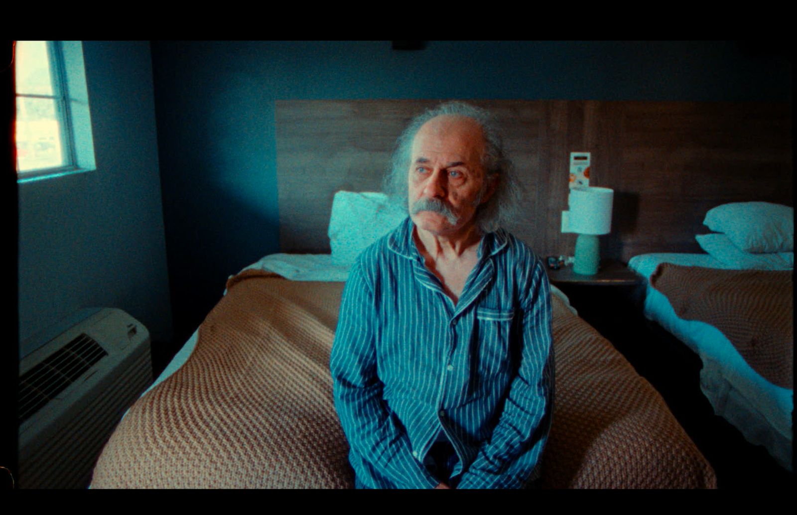 Ümit Mesut seated in a hotel room during filming